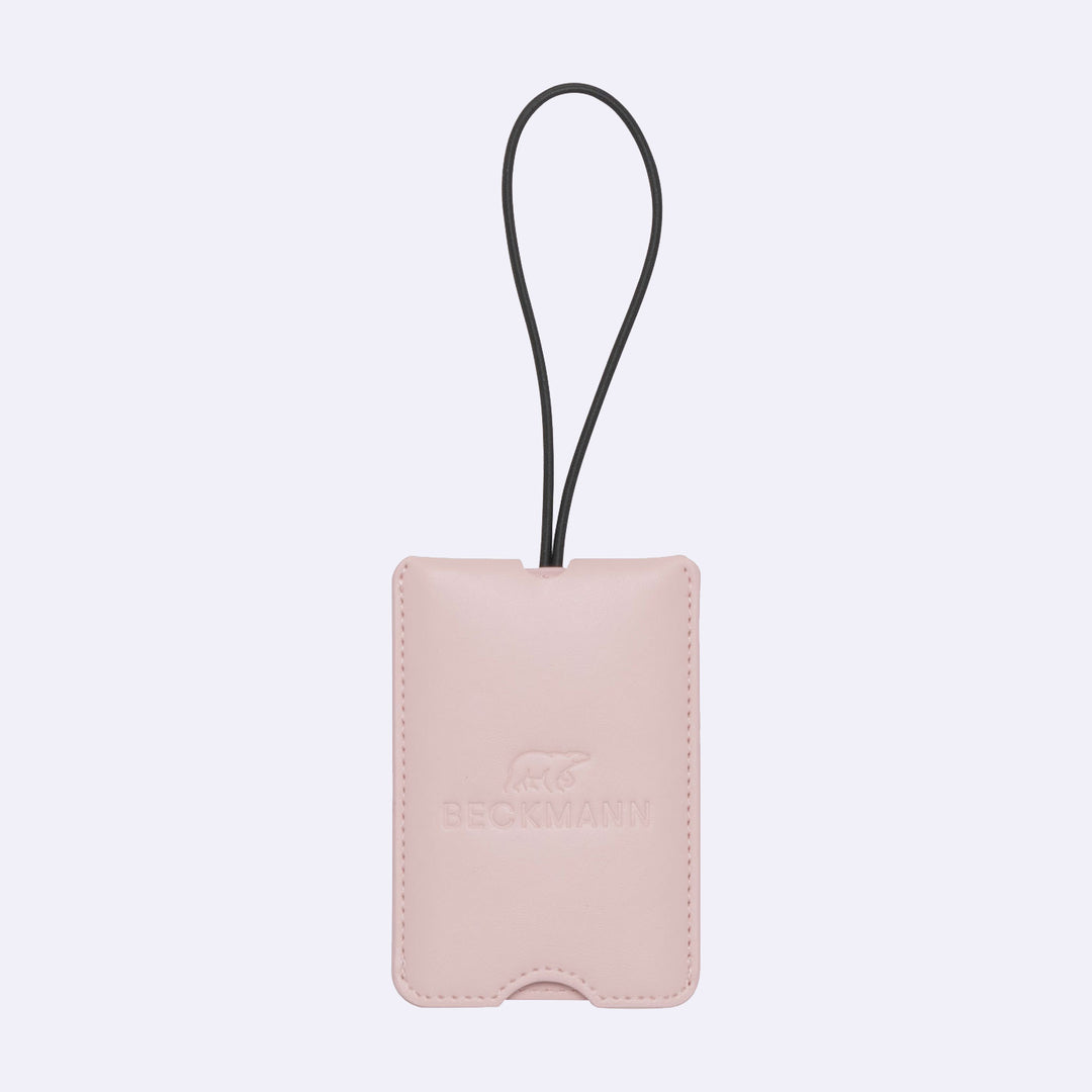 Pink leather luggage tag with a black strap on a light purple background