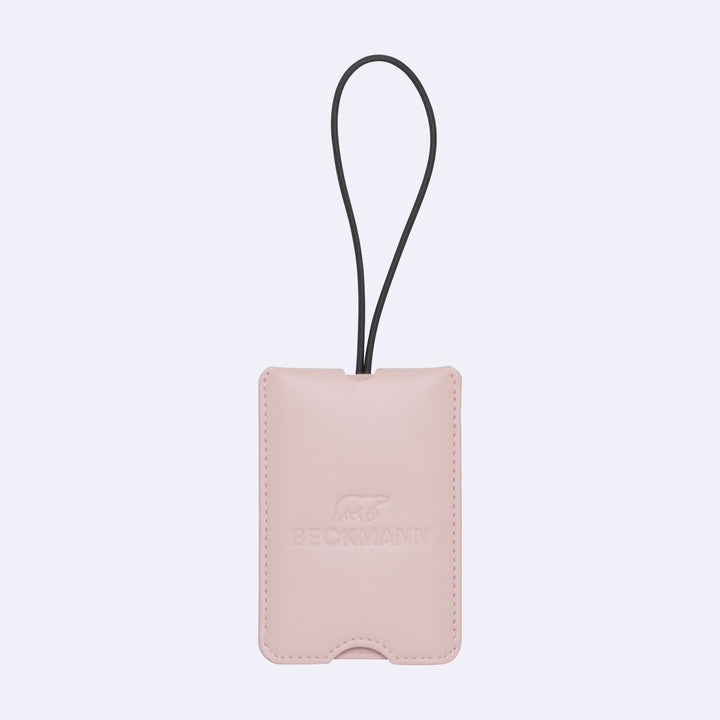 Pink leather luggage tag with a black strap on a light purple background