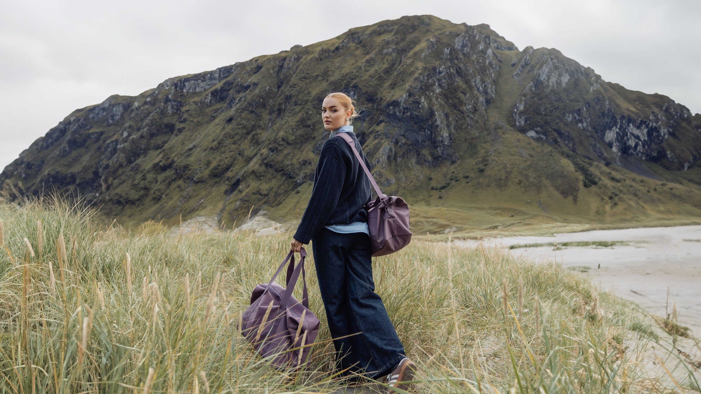 Young woman traveling in the west of norway with weekendbag set. 